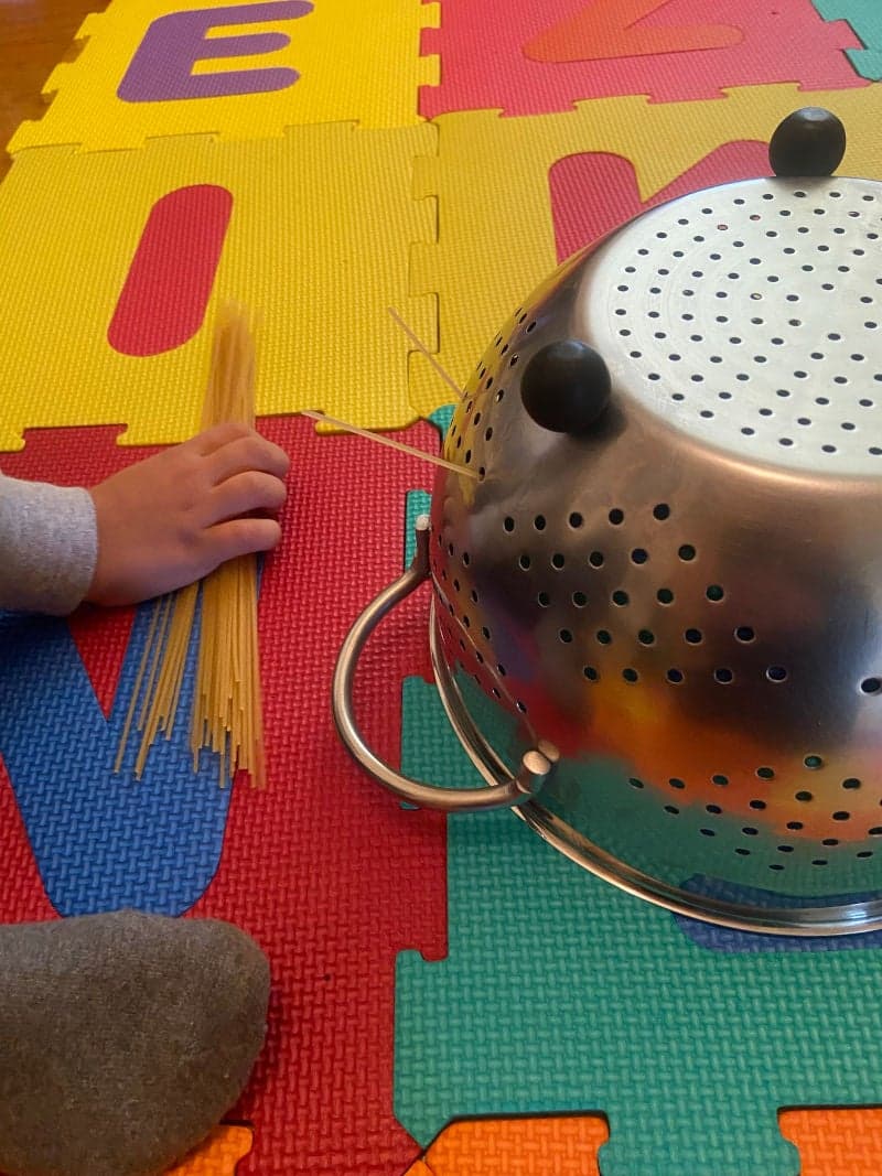 Educational play for preschoolers with spaghetti and colander. Fine motor skills.