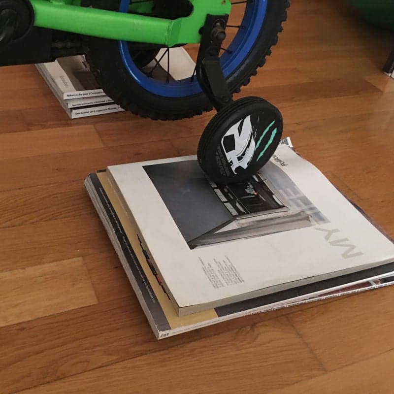 Bicycle in the house. Magazines or books under the training wheels. Inventive way to keep kids active.