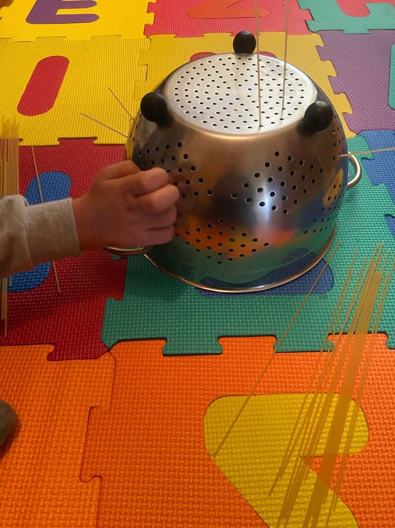Educational play for preschoolers with spaghetti and colander. Fine motor skills.